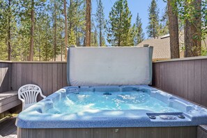 A hot tub with a wooden deck and a white chair, surrounded by a wooden fence and tall trees. - 1 Colonial- Primary Suites, Hot Tub, SHARC, A/C, Steps to Village & SHARC! (Sunriver)