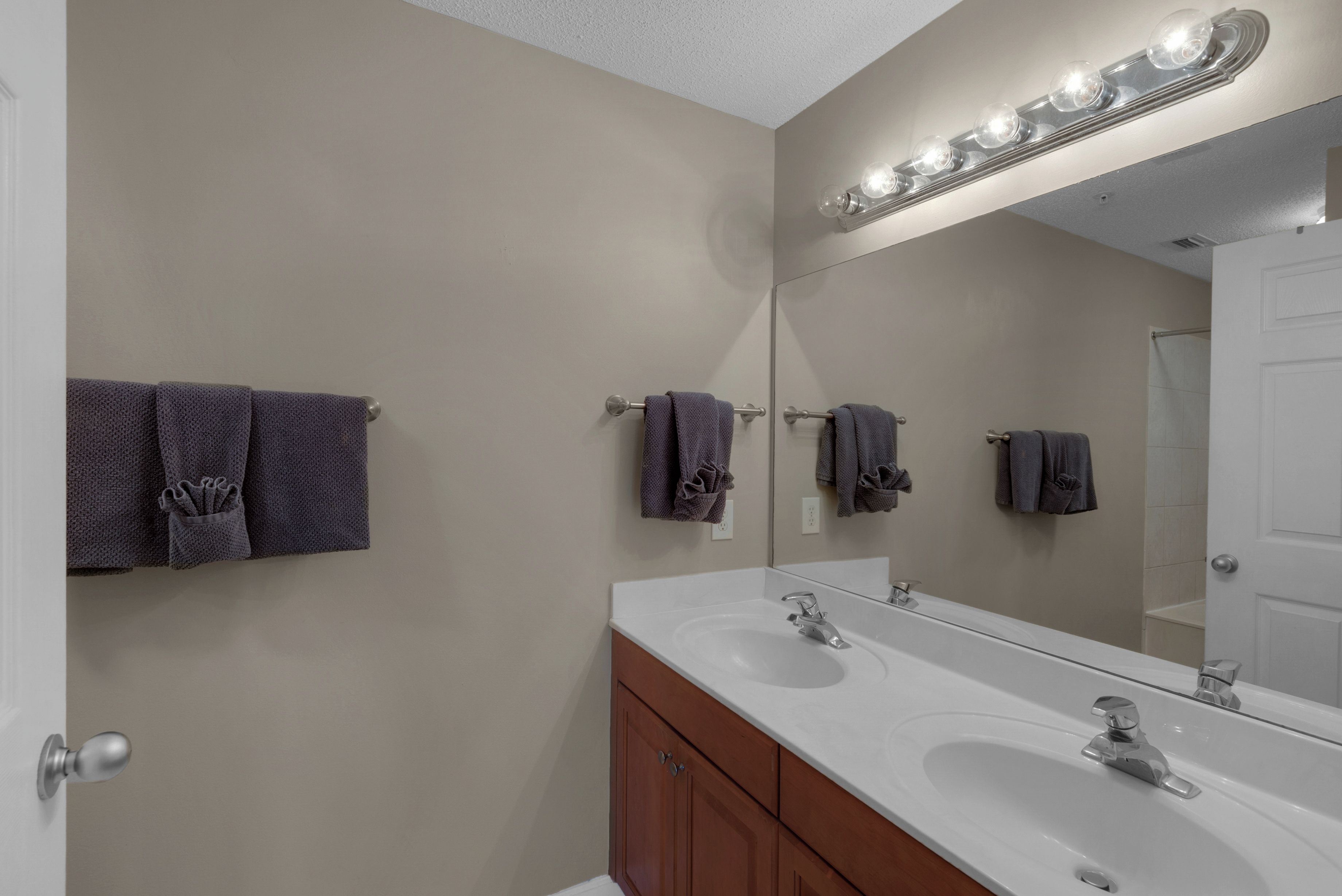 Une salle de bain avec un double lavabo, un grand miroir avec éclairage intégré et des serviettes suspendues sur un porte-serviettes.