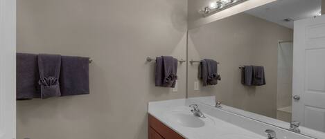 Une salle de bain avec un double lavabo, un grand miroir avec éclairage intégré et des serviettes suspendues sur un porte-serviettes.