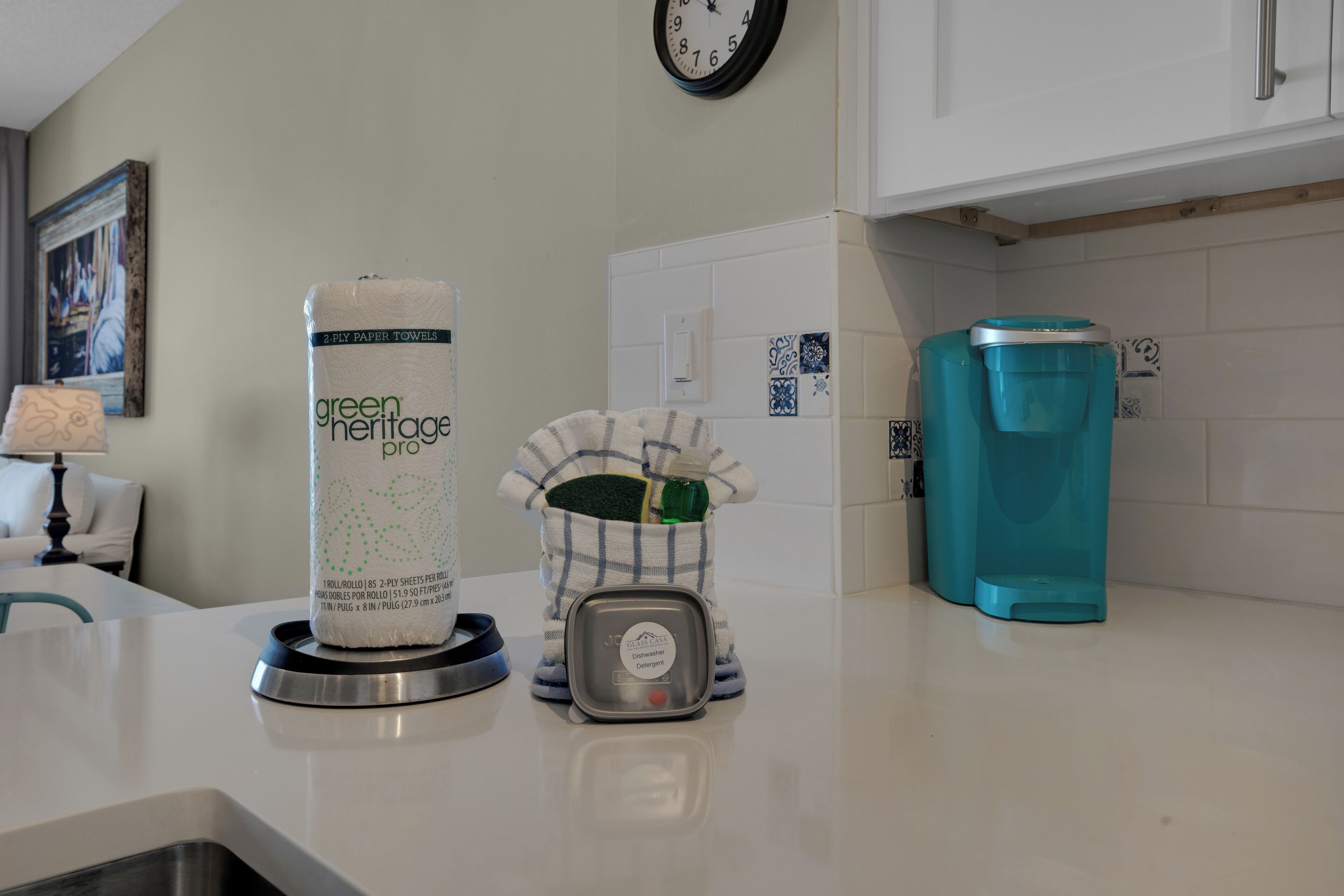 A kitchen counter with a roll of green heritage paper towels, a dish soap dispenser, and a teal water dispenser.