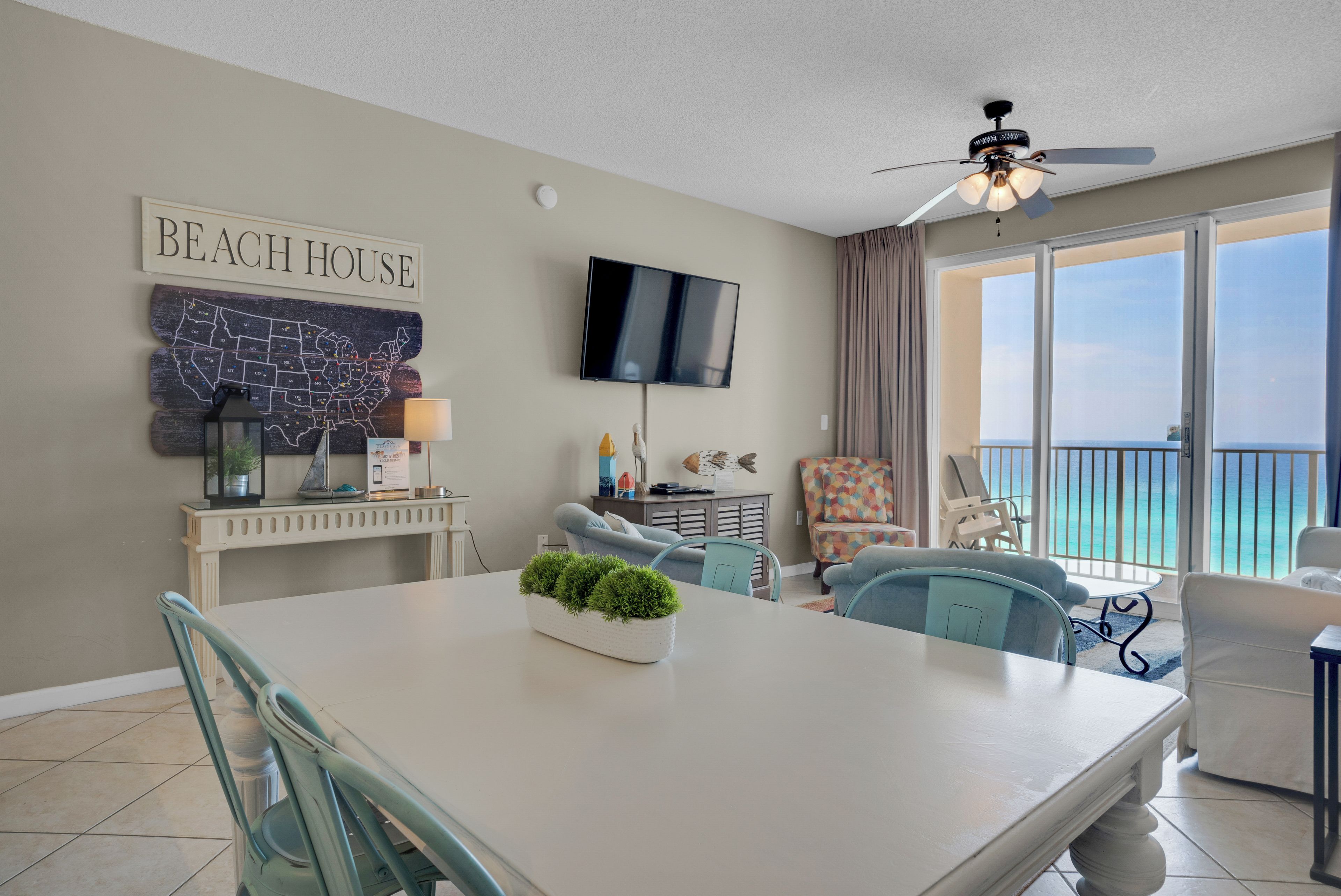 Ein wohnzimmer im Strandhausstil mit Esstisch, Stühlen, einem Fernseher und Blick auf den Ozean.