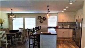A modern kitchen with a central island, wooden flooring, and white cabinetry. - Three Bedroom, Three and a Half Bath. Private Boat Slip. Communal Pool. (Port Mansfield)