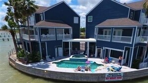 A two-story building with a swimming pool in the center. - Three Bedroom, Three and a Half Bath. Private Boat Slip. Communal Pool. (Port Mansfield)