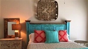 A bedroom with a bed, a nightstand, a lamp, and a wall-mounted decorative item. - Three Bedroom, Three and a Half Bath. Private Boat Slip. Communal Pool. (Port Mansfield)