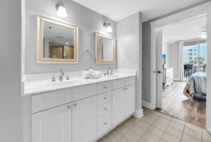 Une salle de bain moderne dotée de deux vasques, de grands miroirs et donnant sur un balcon.