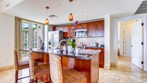 A modern kitchen with a central island, wooden cabinets, a microwave, and a sink.