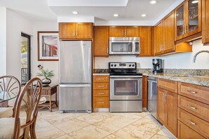 A kitchen with wooden cabinets, stainless steel appliances, and a granite countertop.
