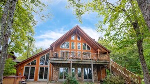 A log cabin with a balcony, large windows, and a staircase leading to a deck. - Dog Friendly Retreat w/ Indoor Pool, Hot Tub & Spa (Mchenry)