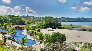 A resort with multiple swimming pools, a beach area, and lush greenery. - Luxury Family Condo, access to Amenities, Beach club + Concierge Service (Herradura)