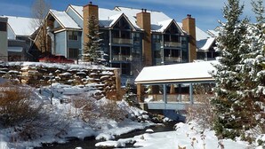 A hotel with multiple buildings, a stone retaining wall, and a snow-covered landscape with a stream.