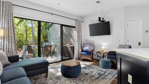 Ein modernes Wohnzimmer mit einer Couch, einem Hocker und einem an der Wand befestigten Fernseher.