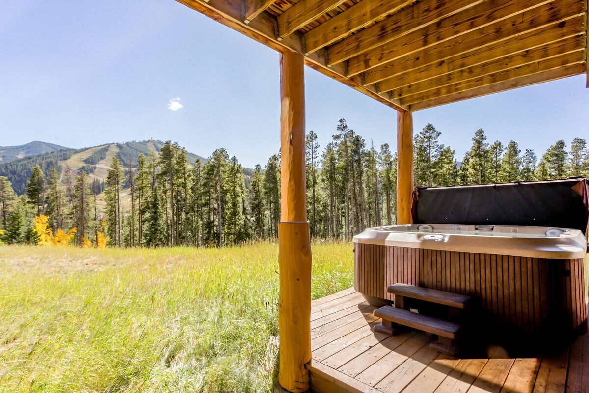 A hot tub on a wooden deck with a mountain view.