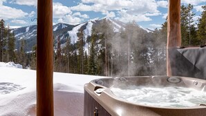 Un bain à remous avec vue sur des montagnes enneigées et des pins.