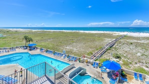 A pool area with clear blue water, a wooden deck, and lounge chairs.