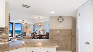 A kitchen with granite countertops, white cabinetry, and a dining area with a view.