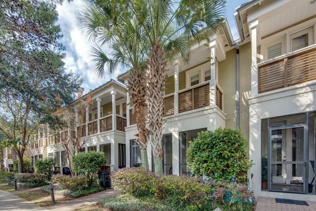 A row of two-story buildings with balconies, surrounded by well-maintained landscaping and trees.