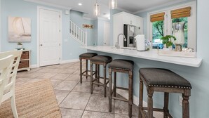 A kitchen with a white countertop, three stools, and a hanging light fixture. - Best of Gulf Place at Your Doorstep Heated pools/Walk to Shops/Restaurants (Santa Rosa Beach)