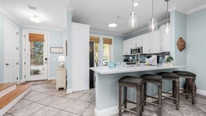 A kitchen with a central island, white cabinets, and a bar stool seating area. - Best of Gulf Place at Your Doorstep Heated pools/Walk to Shops/Restaurants (Santa Rosa Beach)