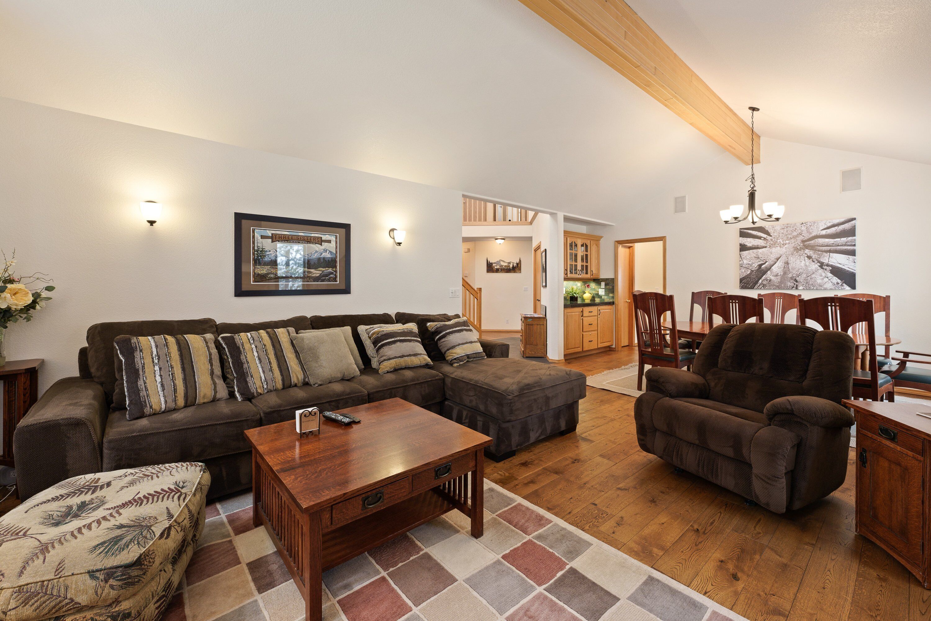 A living room with a sectional sofa, a wooden coffee table, and a dining area with a chandelier.