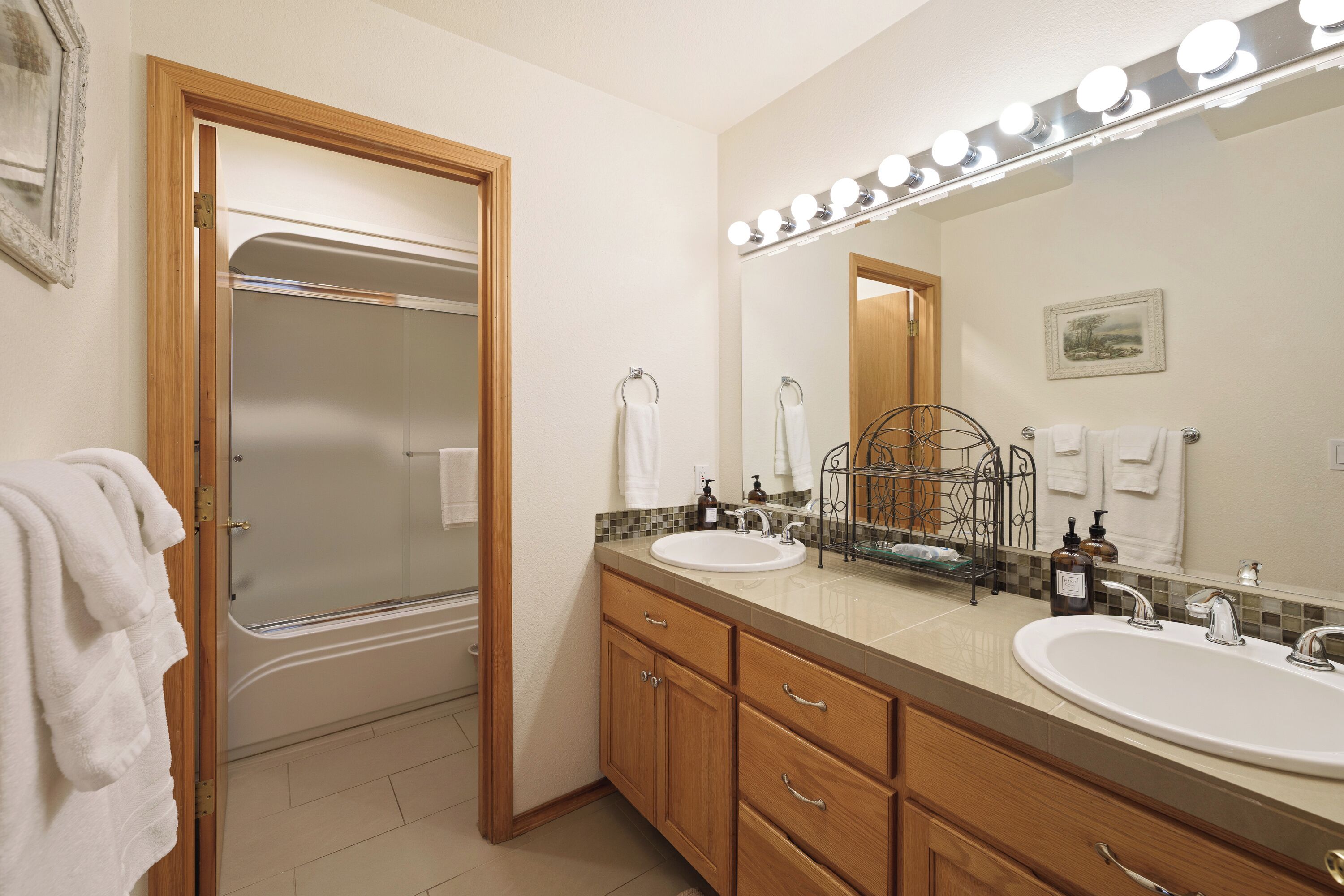 A bathroom with two sinks, a shower, and a vanity with drawers.