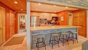 Una cucina moderna con mobili in legno, una grande isola con sgabelli da bar e una parete di fondo in pietra.