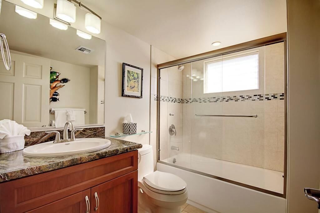 A bathroom with a sink, mirror, toilet, and a glass-enclosed shower.