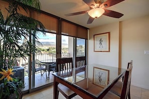 A dining area with a glass table, chairs, and a ceiling fan.