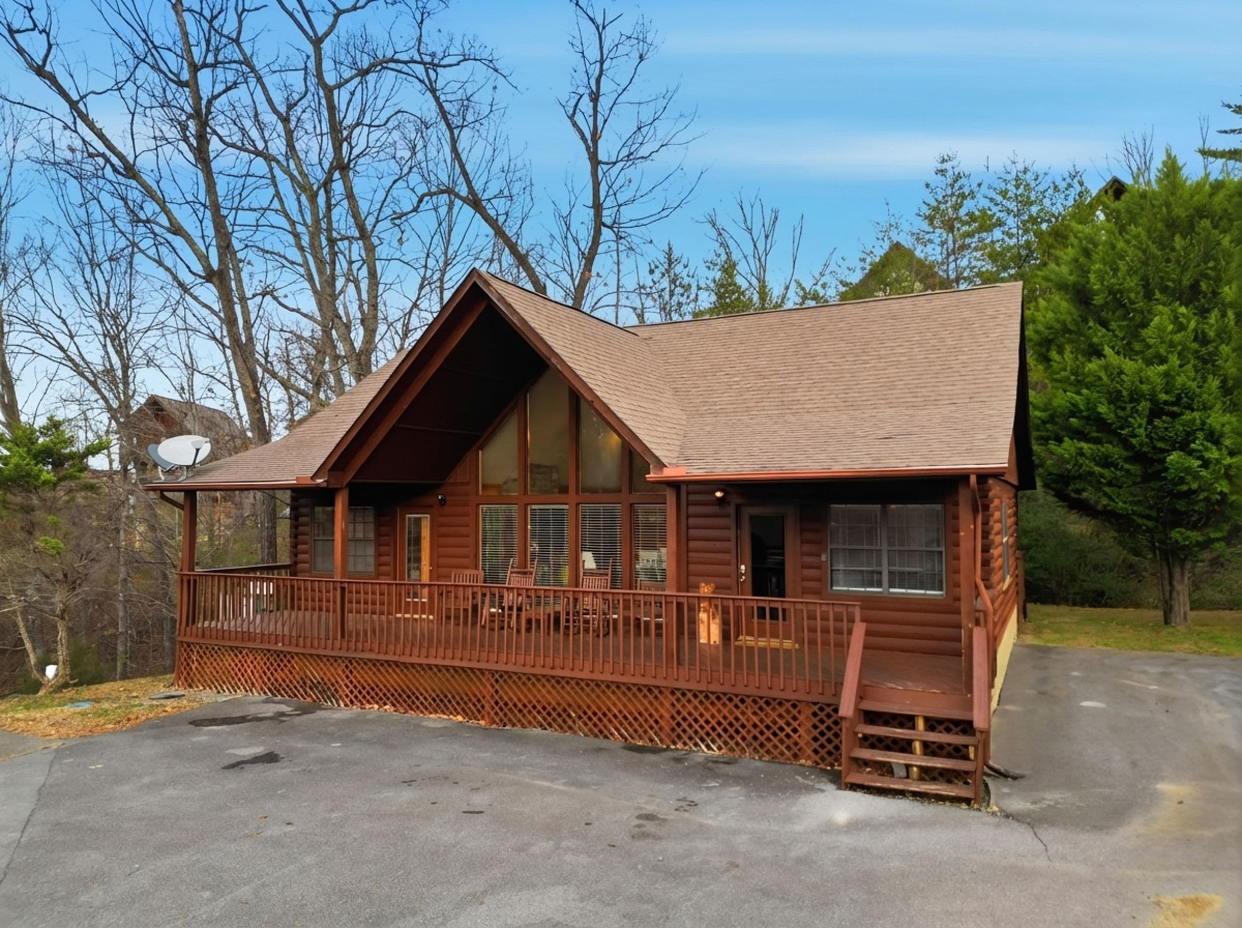 A log cabin with a porch, large windows, and a satellite dish.