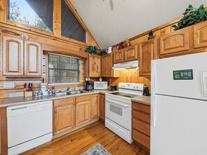 A kitchen with wooden cabinets, a dishwasher, a stove, and a refrigerator.