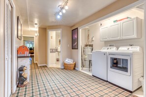 Convenient laundry facilities feature two washing machines and a dryer, along with a wicker basket for storage.