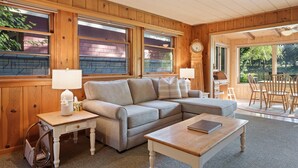 A cozy living room with a sectional sofa, a wooden coffee table, and a small side table with a lamp. - Mirror Pond - Cozy Cabin Directly on Mirror Pond - Deschutes River! (Bend)