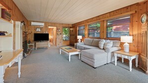 A cozy living room with a sofa, coffee table, and side tables. There is a television and a fireplace. - Mirror Pond - Cozy Cabin Directly on Mirror Pond - Deschutes River! (Bend)