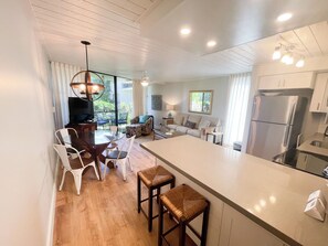 A modern kitchen with a central island, white cabinetry, and stainless steel appliances.