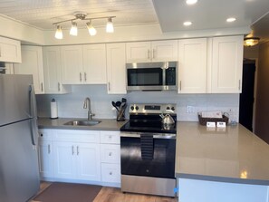 A modern kitchen with white cabinets, stainless steel appliances, and a large island.