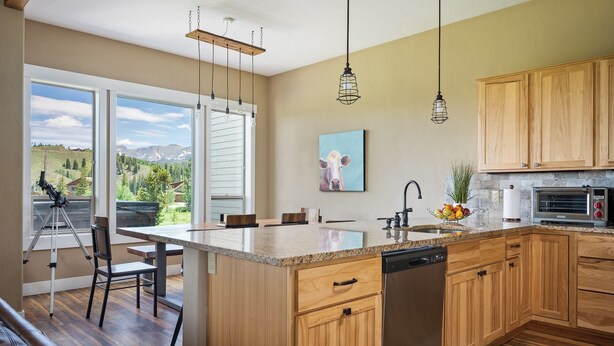 A modern kitchen with wooden cabinets, a large island, and a view of the outdoors.