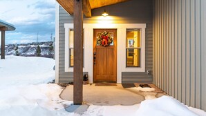 A house with a wooden door, a wreath, and a light above the door.