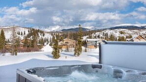 A snow-covered landscape with a hot tub in the foreground and houses in the background.
