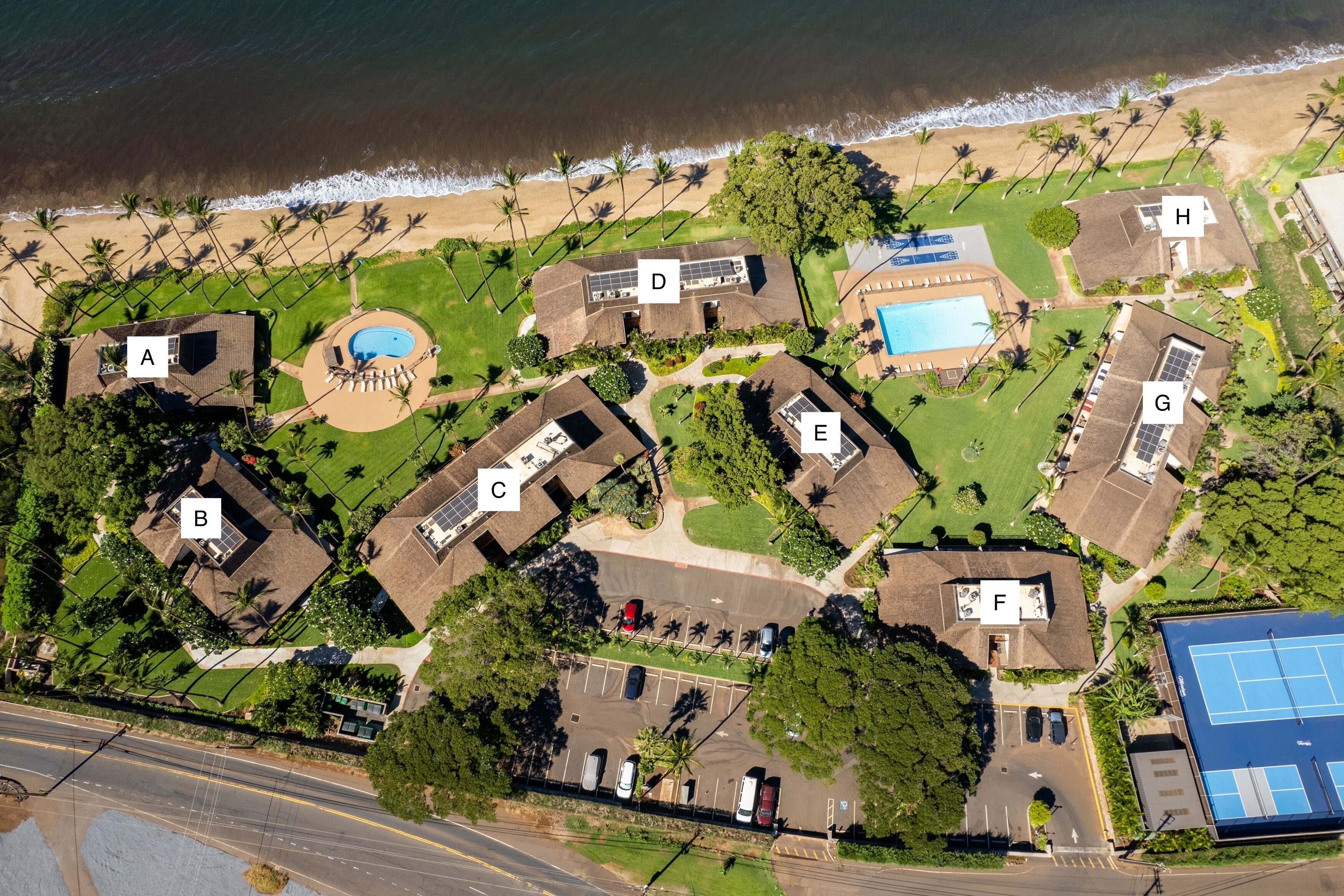 Vista aérea de una zona residencial costera con casas identificadas de la A a la H, una piscina y una cancha de tenis.