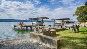 Un muelle a orillas del lago con barcos, mesas de picnic y sillas.