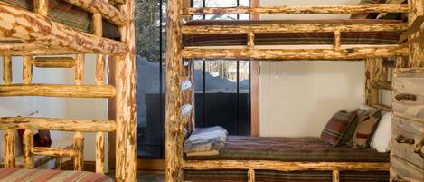A rustic cabin-style room with a bunk bed, a wooden dresser, and a patterned rug.