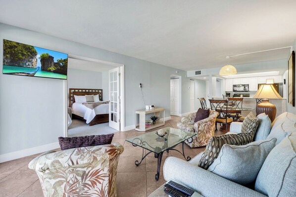 A modern living room with a sofa, a glass coffee table, and a television mounted on the wall.