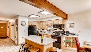 Una cocina moderna con armarios de madera, una isla central con taburetes, un microondas y una cafetera.