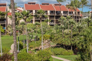 Um hotel com várias varandas, vegetação exuberante e um jardim bem cuidado com um caminho.
