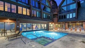 Ein modernes Gebäude mit Schwimmbad, großen Fenstern und Außenbereich mit Sitzgelegenheiten.