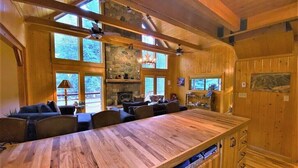 A wooden interior with a long dining table, multiple chairs, a fireplace, and large windows. - Stunning Riverside Cabin, Private Hot Tub, Spacious Yard, Grill (Durango)