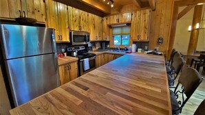 A kitchen with wooden cabinets, stainless steel appliances, and a large wooden island. - Stunning Riverside Cabin, Private Hot Tub, Spacious Yard, Grill (Durango)
