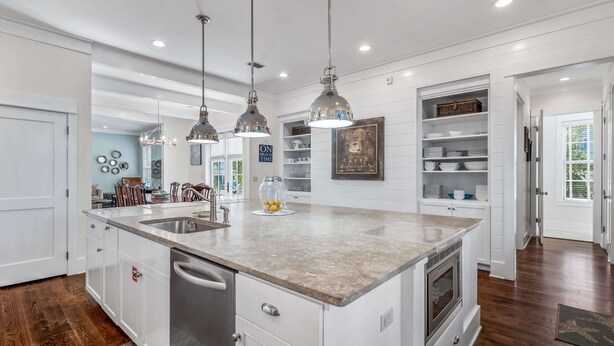 A modern kitchen with a large island, pendant lights, built-in shelving, and a view to the dining area. - Great for Large Groups. 1 Minute to Beach. Private Heated Pool. Carriage House (Watersound)