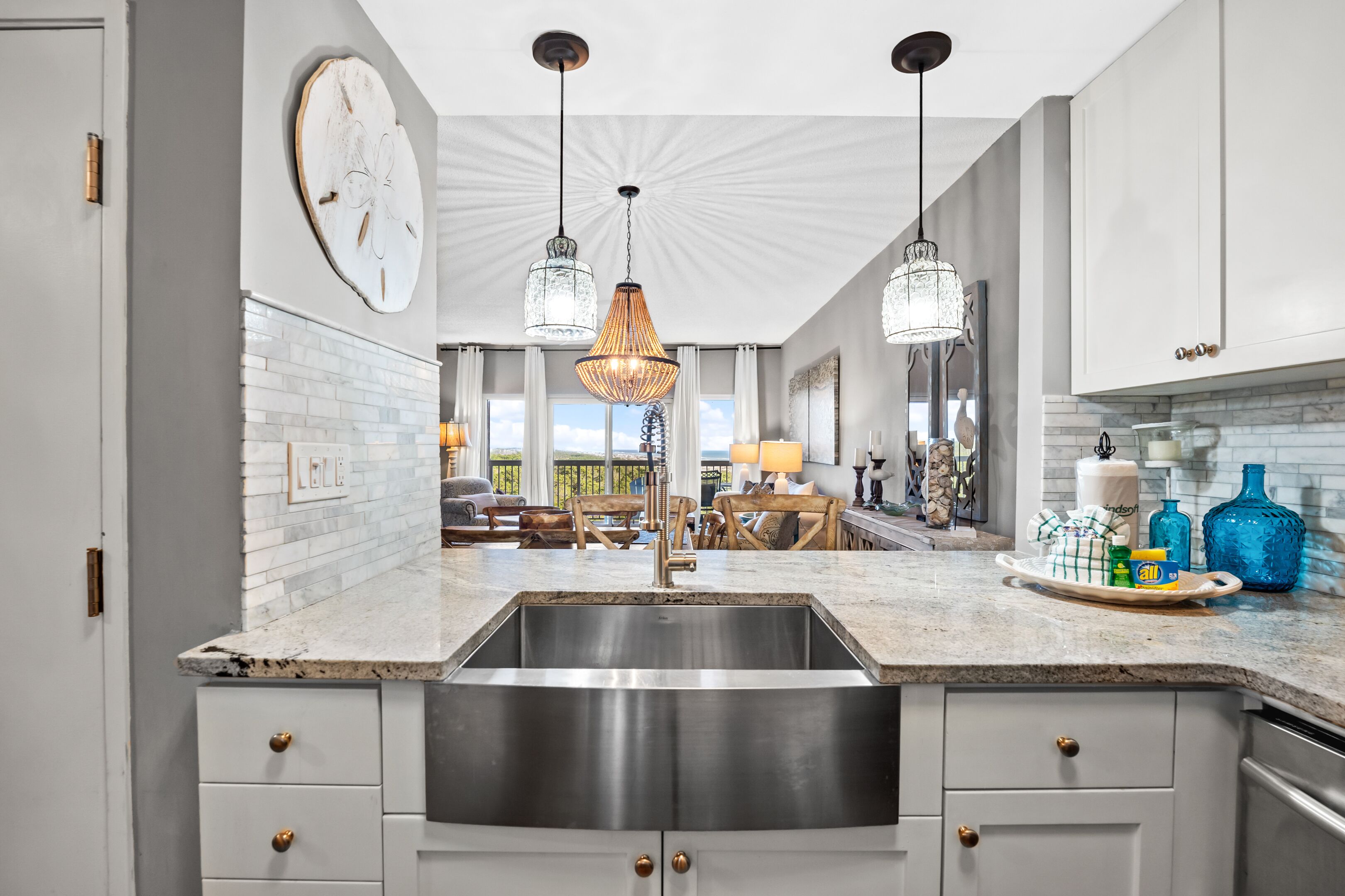 A modern kitchen with a large island, stainless steel sink, and pendant lighting.