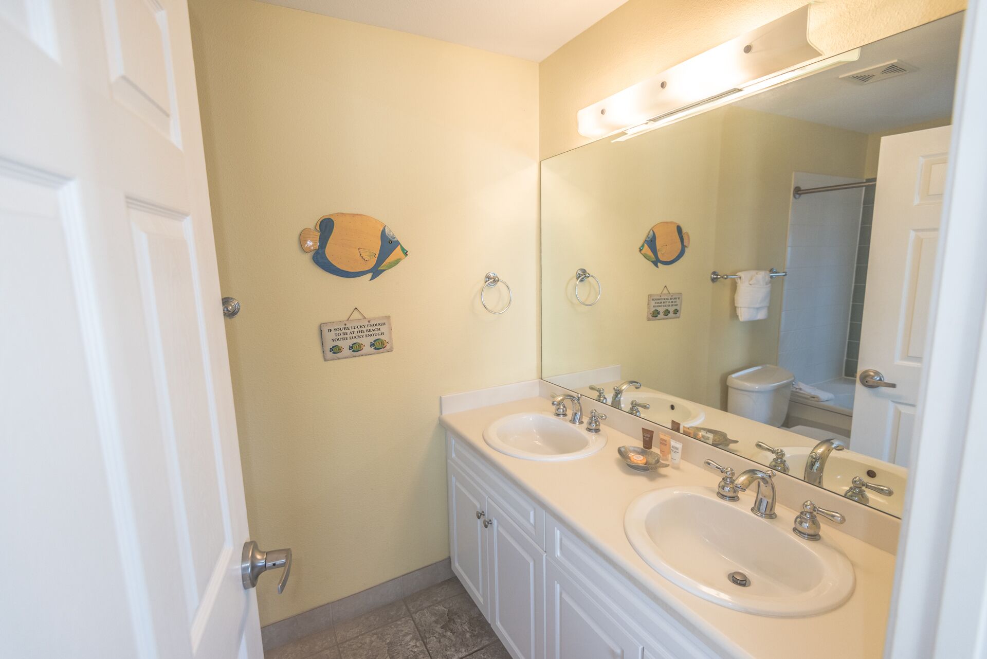 A bathroom with two sinks, a large mirror, and a towel rack.