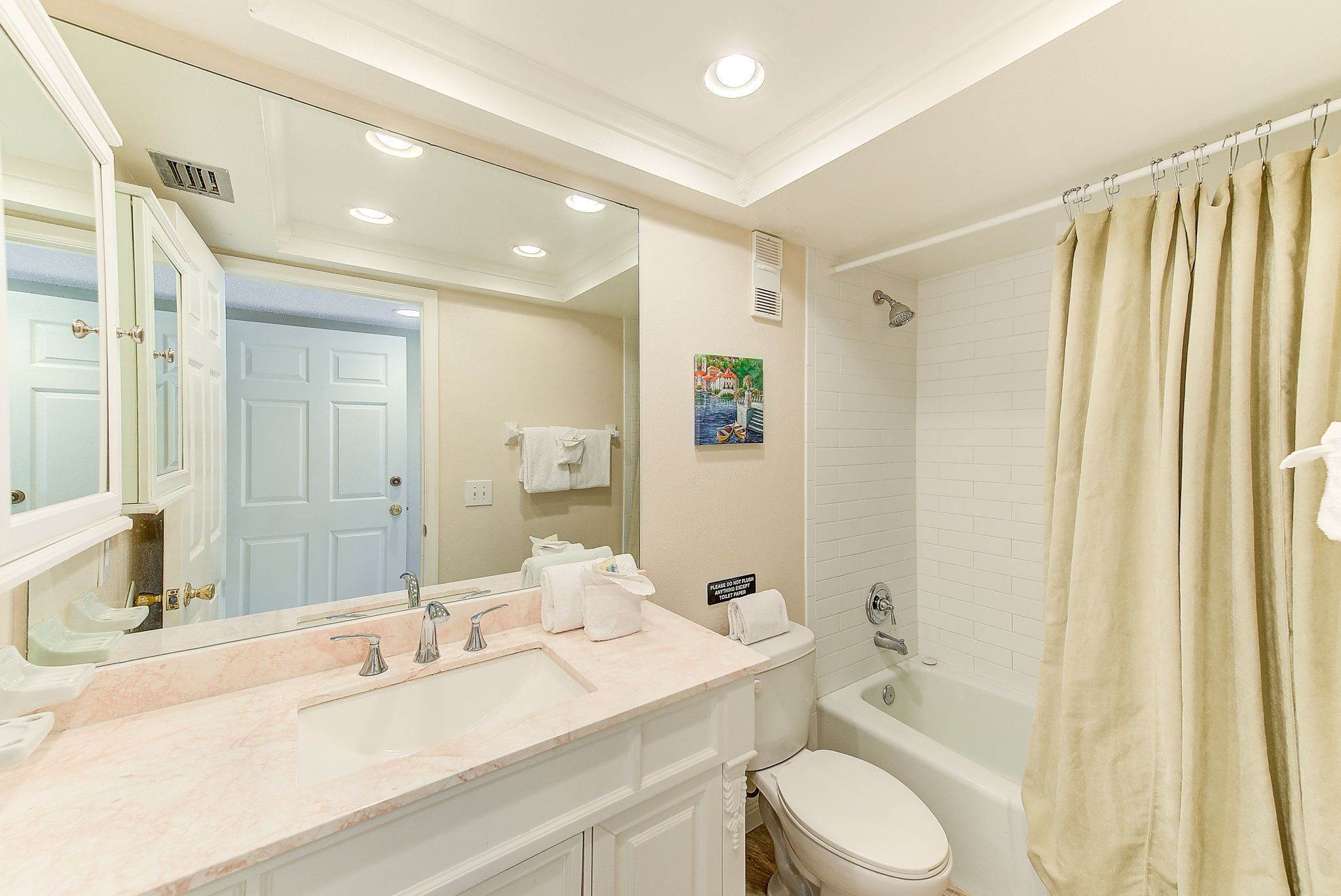 A bathroom with a sink, mirror, toilet, and shower curtain.
